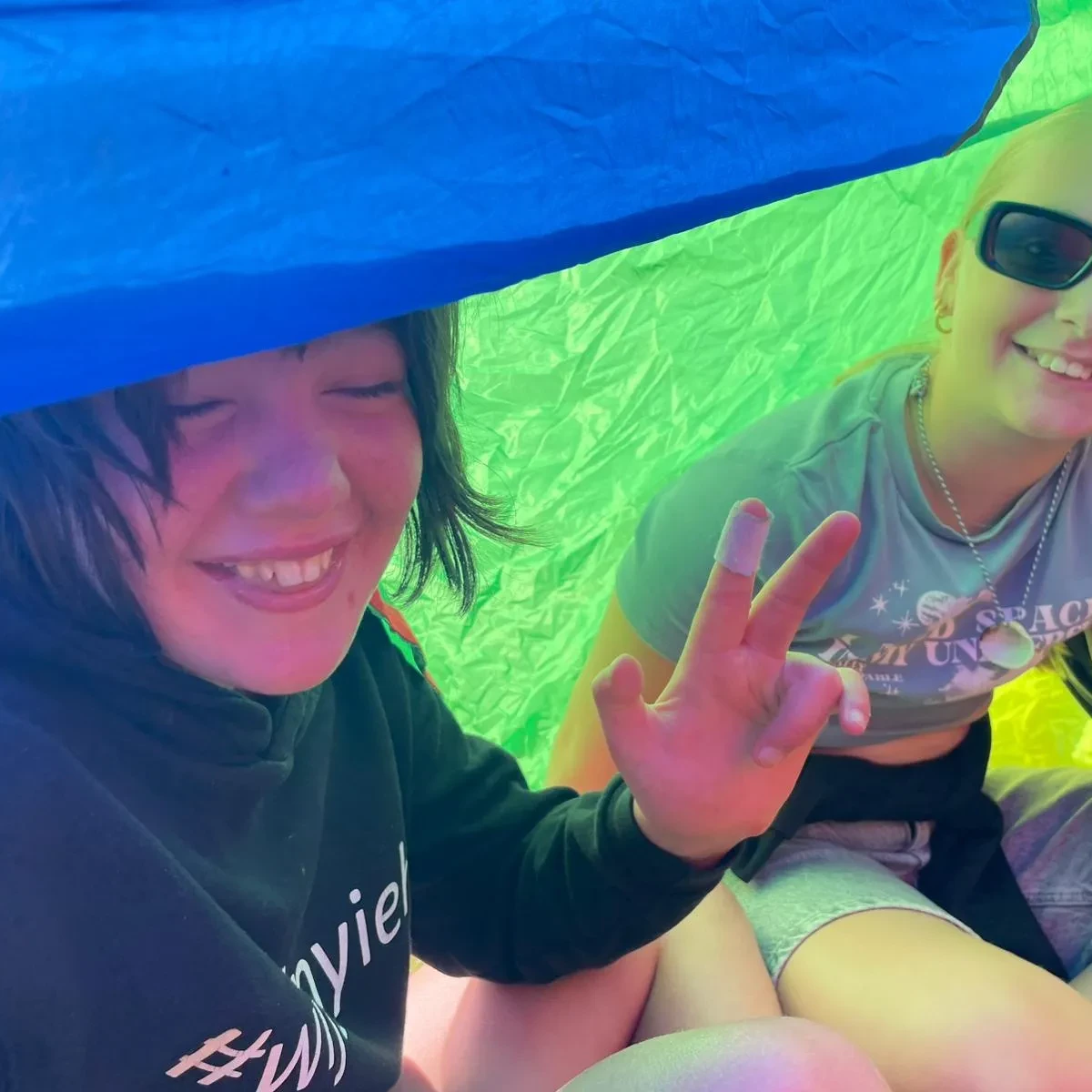 Twee meisjes lachen onder een gekleurde parachute.