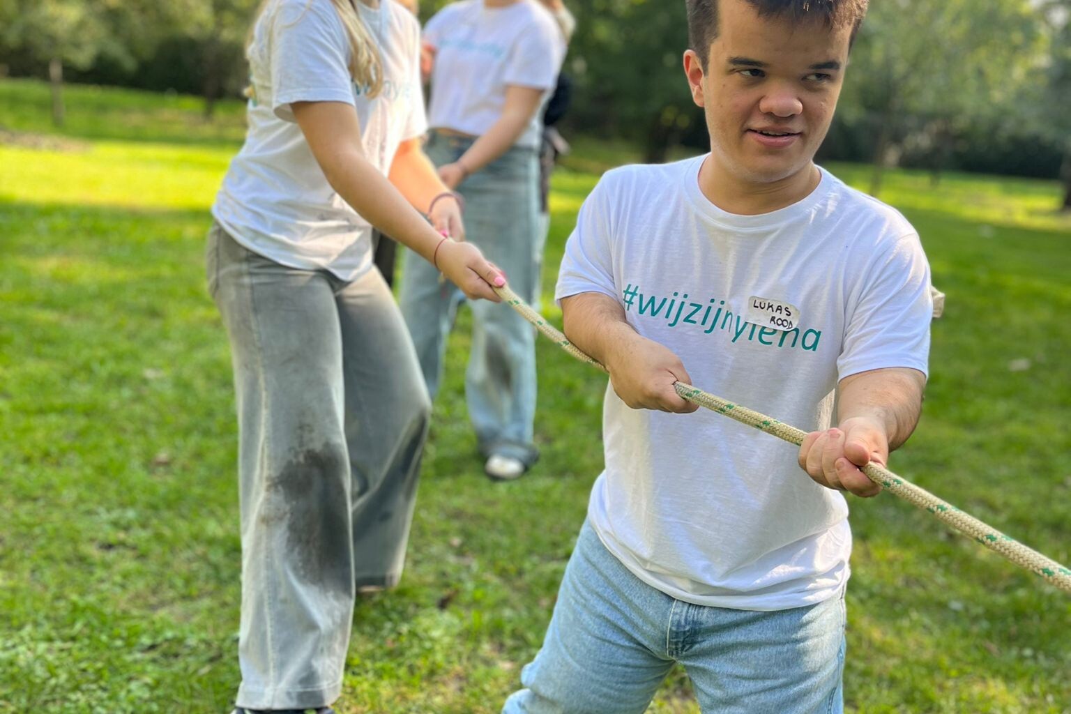 Een jongen trekt aan een touw tijdens een buitenspel met andere kinderen.